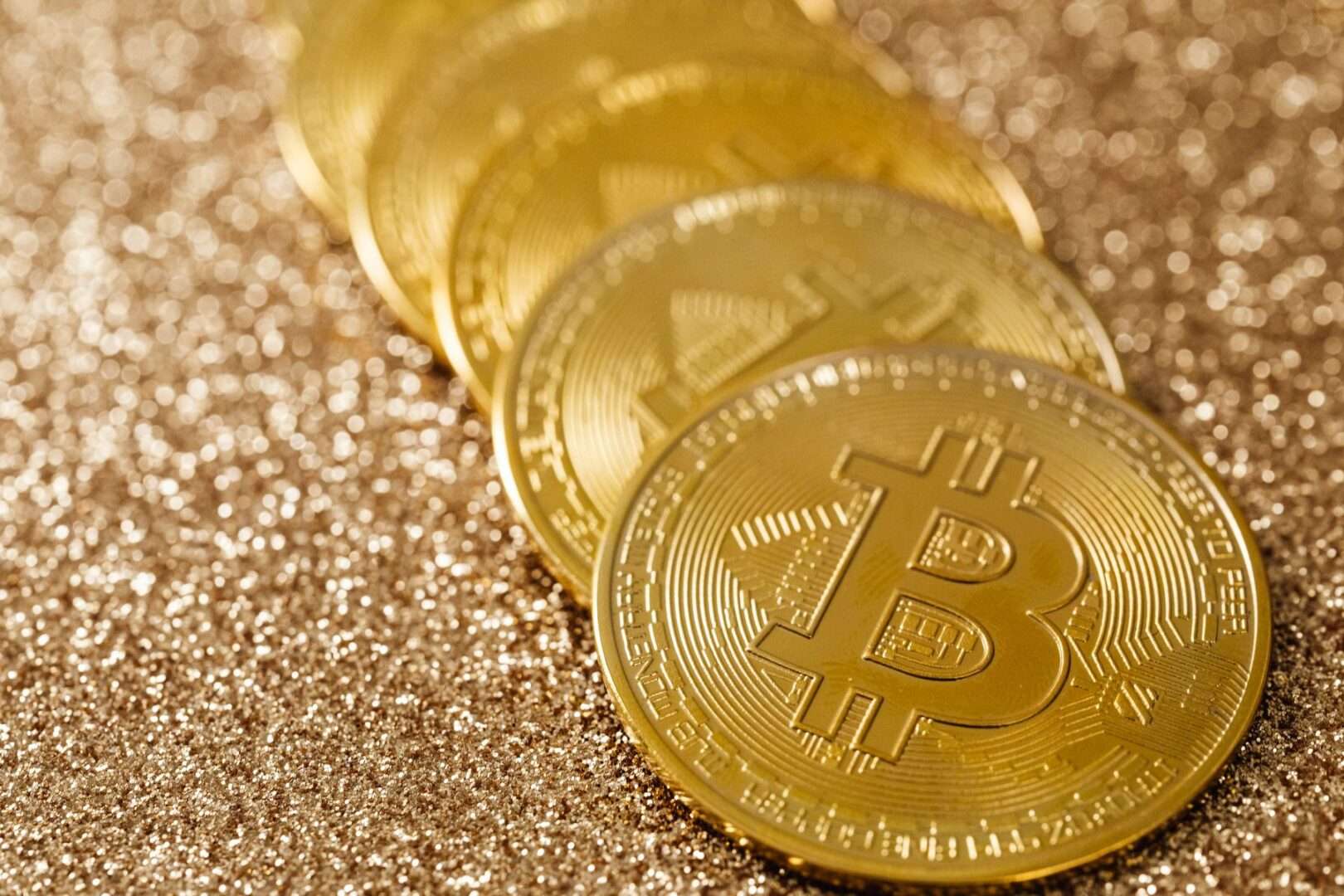 Stack of gold Bitcoin coins on a glittering gold background