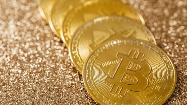 Stack of gold Bitcoin coins on a glittering gold background
